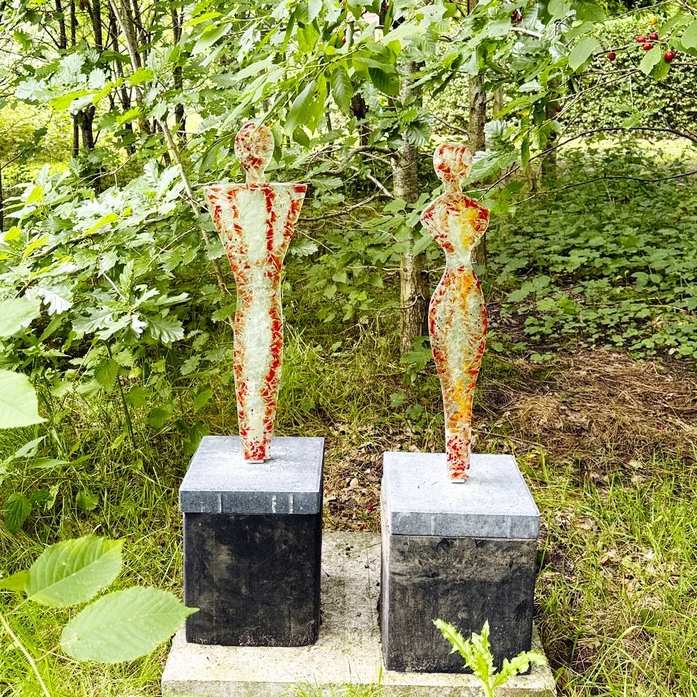 Orangegule skulpturer i glas forestillende 2 mennesker